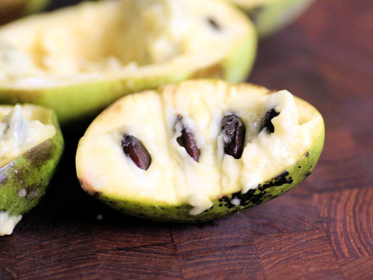 Ripe pawpaw fruit cut open, showing creamy flesh and dark seeds
